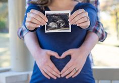 a woman holding up a photo with her hands in the shape of a heart