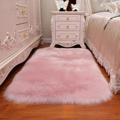 a pink rug is in front of a white dresser and bed with an ornate headboard