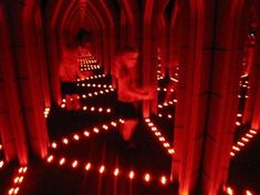 a person standing in the middle of a room filled with candles