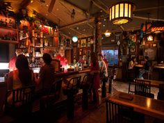 people are sitting at the bar in a restaurant with many decorations on the walls and ceiling