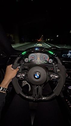 a man driving a car at night with his hands on the steering wheel and dashboard