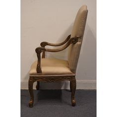 an antique chair is upholstered against a white wall and carpeted flooring