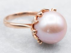 This stunning ring is filled with shades of pink and rose! This is a blushing pink pearl, shining bright and filled with luster. Surrounding the pearl is a botanical mounting set with high-quality diamonds, bringing glitter and light into this dreamy cocktail piece.Metal: 14K Rose Gold Gem: Pink Pearl Gem Measurements: 13.6 mm, RoundAccents: 48 Diamonds totaling .20 Carats Ring Size: 7Marks: "14K IPS" Stamped on the inside band Luxury Rose Gold Pearl Ring In Fine Jewelry Style, Luxury Rose Gold Pearl Ring With Diamond Accents, Luxury Rose Gold Pearl Ring Fine Jewelry, Pink Pearl Rings, Pink Pearl Gold Jewelry, Pearl And Diamond Cocktail Rings, Pink Pearl Jewelry, Pink Pearl Ring, Shiny Rings