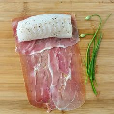 raw meat on a cutting board next to green beans and seasoning sprigs