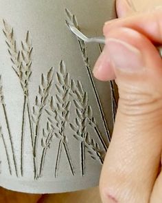 a person is using a sharp knife to cut out the design on a ceramic vase