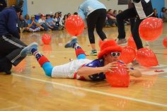 a group of people on a basketball court with red balloons in the shape of clowns