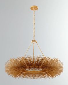 a gold chandelier hanging from a chain with long, thin straws on it