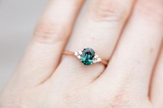 a woman's hand with a green and white diamond ring on her left hand