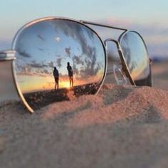 a pair of sunglasses sitting on top of a sandy beach