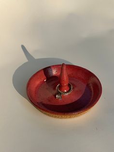 a small red plate with a ring on the edge and a shadow cast by it