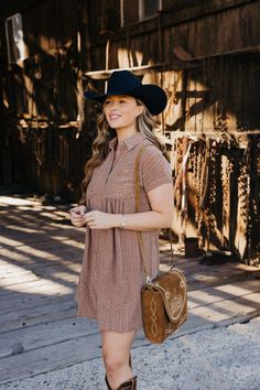 Introducing The Zuri Dress, a playful knee-length western dress in a gorgeous rust color. Made from textured fabric, this dress features a flattering fit and flare silhouette with short sleeves and a v neckline. Complete with a collared button down design and pocket detail, it's the perfect dress for fall fun! Haylee is wearing size small paired with the Ariat Casanova Boots, Felt Cowboy ProHat and The Talia Bag