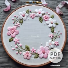 a close up of a embroidery on a hoop with flowers and leaves in the center