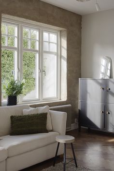 a living room filled with furniture and a large window next to a white couch on top of a hard wood floor