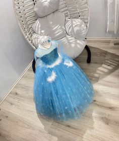 a blue dress sitting on top of a wooden floor next to a white teddy bear