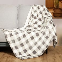 a couch covered with a checkered blanket next to a potted plant