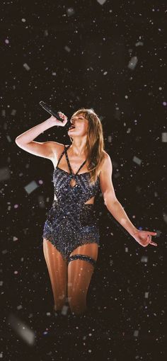 a woman in a bathing suit singing on stage with confetti falling around her