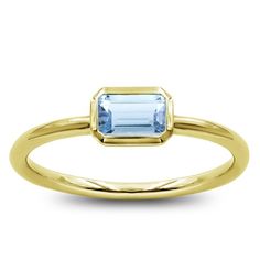 a yellow gold ring with an aqua blue topazte stone in the center, on a white background