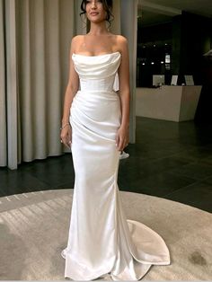 a woman in a white dress standing on a round floor with curtains behind her and looking off to the side