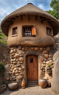 a house made out of rocks with a thatched roof and windows on the side