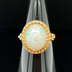 The 4.30 carat opal in this handmade 18k yellow gold ring is bursting with color! This gemstone displays flashes of bright green, orange, yellow, and the most highly-prized and rare color: red! It is difficult for photos to do this opal justice. This ring was custom-designed by our Master Jewelers in Los Angeles in order to showcase the high dome, depth of color and life in this gem. The sides of the ring have been hand engraved and show a level of artisanship and skill seldom seen today. A ring Yellow Gold Ethiopian Opal Ring In Oval Cabochon Shape, Yellow Gold Ethiopian Opal Oval Cabochon Ring, Yellow Gold Ethiopian Opal Ring In Oval Shape, Ethiopian Opal Oval Cabochon Ring In Yellow Gold, Collectible Yellow Gold Opal Ring Oval Cabochon, Collectible Oval Cabochon Opal Ring In Yellow Gold, Yellow Gold Cabochon Opal Ring Collectible, Yellow Gold Cabochon Opal Ring For Collectors, Cabochon Yellow Gold Opal Ring Collectible