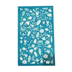 a teal blue and white paper with flowers, leaves and birds on it's side