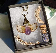 This bronze resin coated pendant features an amethyst crystal bordered by two real cicada brood xix hindwings, and will come strung through a chain (color and length of your choice). Each wing used to create this mystical looking jewelry was ethically collected straight from the ground in Southern Illinois. Wearing this woodland necklace is a perfect way to keep a bit nature with you at all times of the year. You will receive the exact pendant as shown in the pictures. Small bubbles may be present. Fast and free US shipping from Illinois. Each piece of jewelry arrives in woodland themed packaging that is perfect for gift giving. Every order is securely packaged so that it may arrive to you in a safe and timely manner. Are you looking to add a magical touch to your wardrobe? Favorite Fern E Bug Jewelry, Necklace Fairy, Insect Wings, Fairy Necklace, Southern Illinois, Bronze Necklace, Jewelry Post, Botanical Jewelry, Amethyst Crystal