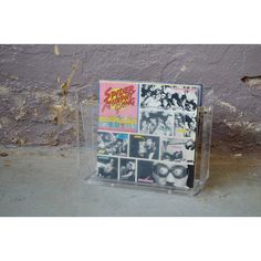 a display case with various records in it on the ground next to a brick wall