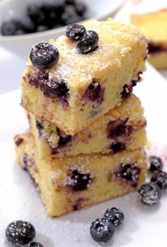 blueberry bars stacked on top of each other with powdered sugar and berries around them