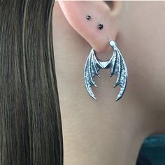 Dragon Wings hoop earrings  are made of 316 Stainless steel and have oxidation, to add more depth and details. Hoops are perfect for both men and women. Total height: 30 mm Total width: 23 mm Gauge: 22G (regular piercing) Listin for 1 pair (2 earrings) *RETURNS / REFUNDS * -If you would like to return you purchase , please contact us within 7 days of receiving your package and we will accept the return.Return will only be made to the product, and not the shipping cost.  -Buyer is  responsible for the return shipping costs . -All jewelry must be returned unworn and in their original condition . *LOST MAIL* Once the package is marked as DELIVERED by the post office, we are not responsible for misplaced or stolen packages. *MAIL THEFT* If parcel is stoled or vandalized, please contact USPS ma Gothic Metal Jewelry With Dragon Design, Gothic Silver Metal Piercings, Alternative Silver Jewelry For Pierced Ears, Gothic Metal Hoop Earrings, Gothic Hoop Earrings Gift, Gothic Hoop Cartilage Earrings, Gothic Hoop Earrings As A Gift, Gothic Sterling Silver Single Cartilage Earring, Gothic Horned Jewelry For Halloween