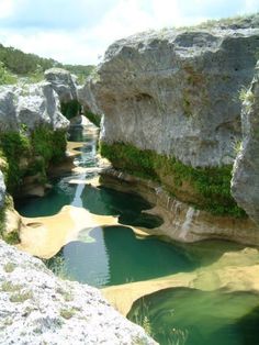 a river running between two large rocks in the middle of a valley with green water