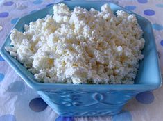 a blue bowl filled with cottage cheese sitting on top of a tablecloth covered table