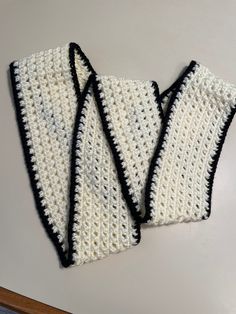 two black and white crocheted bags sitting on top of a table