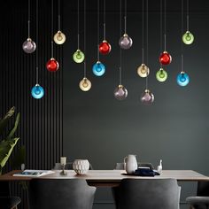 a dining room table with chairs and lights hanging from the ceiling