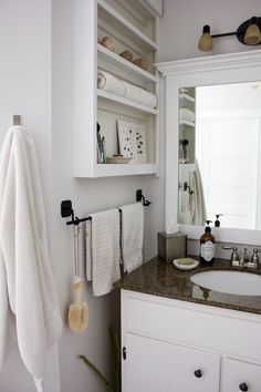 a bathroom with white cabinets and towels hanging on the rack in front of the mirror