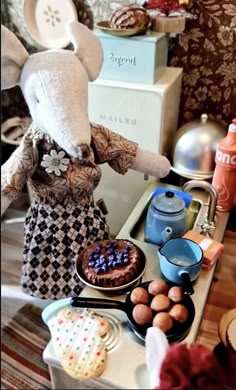 an elephant doll is standing over a table full of food and desserts on it's side