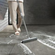 a woman is using a mop to clean the floor in front of a wall