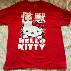 a red hello kitty t - shirt sitting on top of a bed