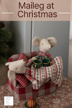 a stuffed mouse sitting on top of a red and white checkered blanket next to a christmas tree