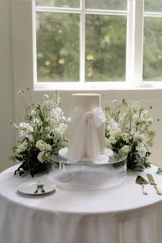 a white wedding cake sitting on top of a table next to flowers and utensils