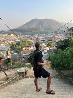 a man with a backpack is walking up some steps and holding a drink in his hand