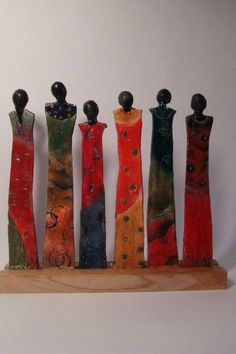 five small wooden figures are lined up in a row on a wood stand, with one standing out from the others