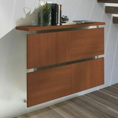 a wooden cabinet with metal handles and drawers on the bottom, next to stairs in an empty room