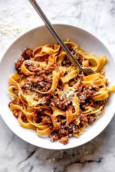 a white bowl filled with pasta and meat