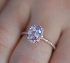 a woman's hand with a ring on it and an oval shaped pink sapphire