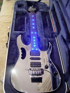 an electric guitar in its case with blue lights on it's body and neck