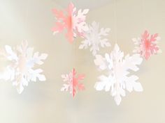 paper snowflakes hanging from the ceiling in front of a wall with white walls