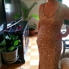 a woman in a sequined dress standing next to a plant and television set