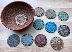 a bowl sitting on top of a wooden table filled with lots of different colored plates