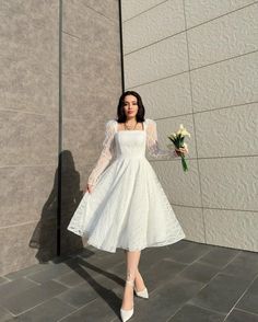 a woman in a white dress holding a flower