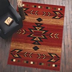 a red and black area rug with an arrow design on the center, sitting on a wooden floor